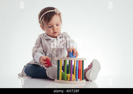 Cute baby girl playing cubes en bois isolé sur fond blanc. Banque D'Images