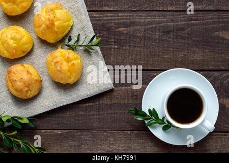 Des petits pains fraîchement cuits et éclairs une tasse de café (espresso) sur un fond de bois foncé. petit-déjeuner léger. La vue de dessus. Banque D'Images