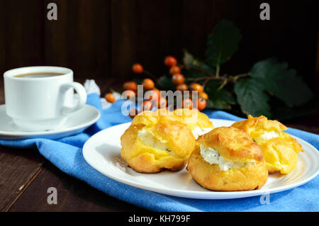 Des petits pains fraîchement cuits au four farcies éclairs épicé avec du fromage cottage et une tasse de café (espresso) sur un fond de bois foncé. petit-déjeuner léger. Banque D'Images