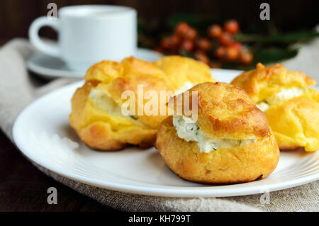 Des petits pains fraîchement cuits au four farcies éclairs épicé avec du fromage cottage et une tasse de café (espresso) sur un fond de bois foncé. petit-déjeuner léger.close up Banque D'Images