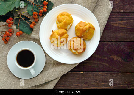 Des petits pains fraîchement cuits au four farcies éclairs épicé avec du fromage cottage et une tasse de café (espresso) sur un fond de bois foncé. petit-déjeuner léger. La vue de dessus Banque D'Images