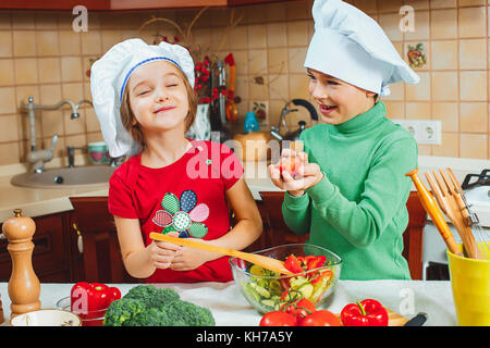 Happy Family funny kids sont la préparation de la salade de légumes frais dans la cuisine Banque D'Images