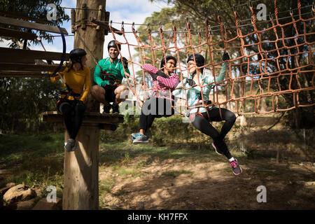 Happy friends relaxing on rope bridge dans adventure park Banque D'Images
