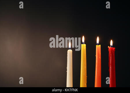 Ensemble de quatre bougies d'éclairage de couleur sur fond sombre Banque D'Images
