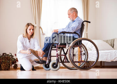 Infirmière et man en fauteuil roulant lors de visite à domicile. Banque D'Images