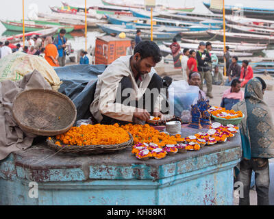 Trader sur les rives du Gange la vente de pétales de fleurs, de guirlandes et lampes à huile miniature ( deeyas ) pour les dévots hindous à utiliser dans des prières rituelles Banque D'Images