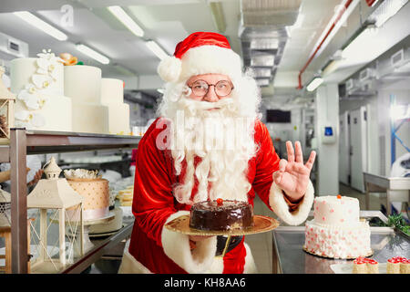 Santa Claus un confiseur prépare un gâteau dans la cuisine sur le christ Banque D'Images