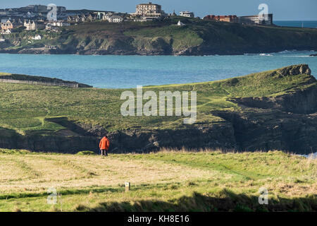 Un homme walker dans une veste rouge vif à marcher le long de la South West Coast Path avec la ville de Newquay Cornwall UK en arrière-plan. Banque D'Images