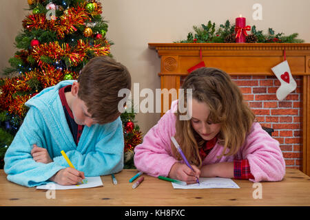 Deux enfants, un garçon et une fille, écrivent leurs lettres au Père Noël Banque D'Images