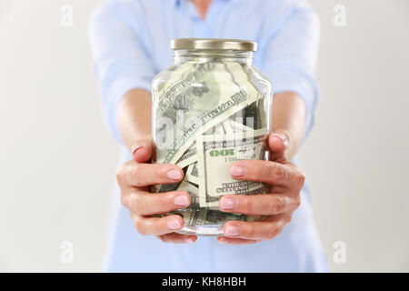 Photo recadrée de womans mains tenant un bocal en verre avec des dollars, isolé sur fond blanc Banque D'Images