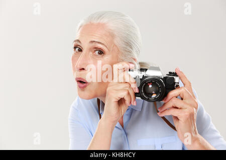 Belle mature surpris dans casual woman holding retro camera plus islated white Banque D'Images
