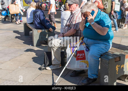 Des gens assis sur des bancs dans Northumberland Street, Newcastle City Centre sur une journée ensoleillée. Banque D'Images