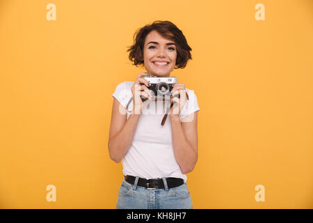 Portrait of a smiling cute girl retro camera while isolés sur fond jaune Banque D'Images