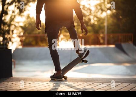 Jeune homme africain faisant le skate dans un skate park en plein air Banque D'Images