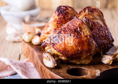 Cuisses de poulet rôti à l'ail sur la planche à découper en bois rustique Banque D'Images