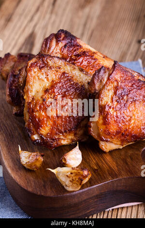 Cuisses de poulet rôti à l'ail sur la planche à découper en bois rustique Banque D'Images