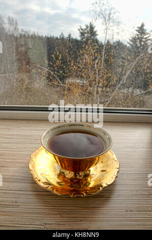 Plaqué or magnifique tasse de thé se tient sur le rebord Banque D'Images