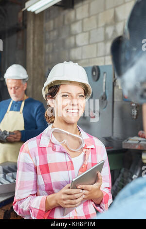 Jeune femme comme apprenti ferronnier avec coffre en métallurgie factory Banque D'Images