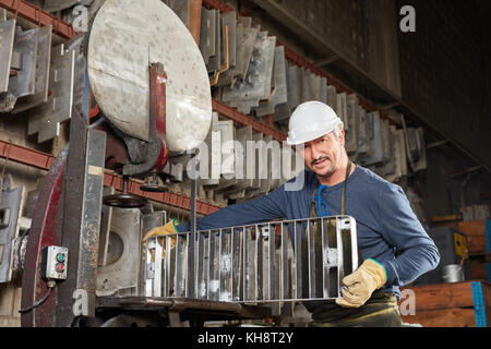 L'homme comme col bleu en usine avec plaque de moule de la métallurgie Banque D'Images