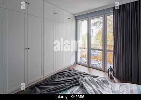 Chambre à coucher moderne avec grande armoire et fenêtre, blanc Banque D'Images