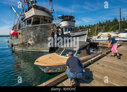 Homme et femme qui liaient un bateau sur la jetée, des bateaux de pêche amarrés à la marina de Quathiaski Cove sur l'île Quadra, dans la région de l'île de Vancouver, en Colombie-Britannique, Can Banque D'Images