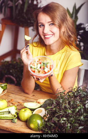 Attractive, slim girl eating de légumes grillés à la table en bois plein d'aliments sains et nutritifs Banque D'Images