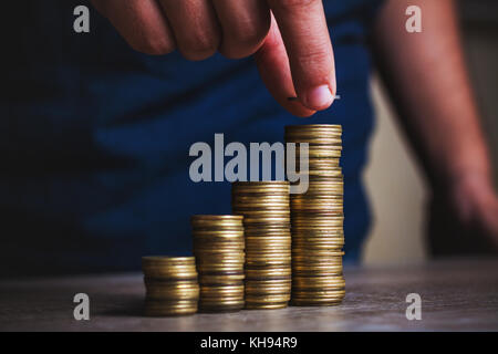 La main de l'homme mettre de l'argent monnaie pour pile de pièces. l'argent, financier, la croissance de l'entreprise concept Banque D'Images