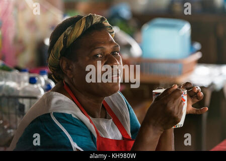 Joanna boire une tasse d'eau chaude. Joanna travaille à Port Vila, marché de fruits et légumes, Vanuatu. Banque D'Images