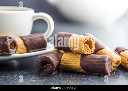 Dessert sucré. rouleaux de biscuits au chocolat avec glaçage sur vieille table de cuisine. Banque D'Images