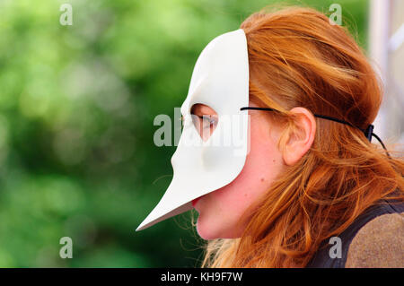 Libre d'une interprète féminine aux cheveux rouges portant un masque sur le Royal Mile, au cours de l'Edinburgh International Fringe Festival Banque D'Images