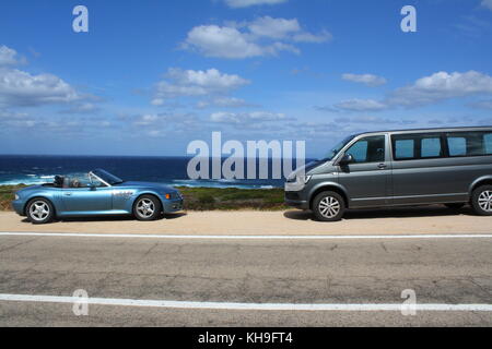 Une voiture de sport cabrio cabrio cabriolet et un minibus wolkswagen, vue panoramique sur une plage en arrière-plan. Banque D'Images