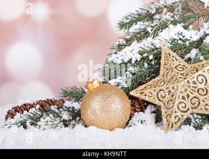 Gold Christmas ball et star avec evergreen tree branch in snow Banque D'Images