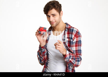 Portrait of a handsome man holding charmant petit cadeau fort et en pointant du doigt sur fond blanc isolé de l'appareil photo Banque D'Images