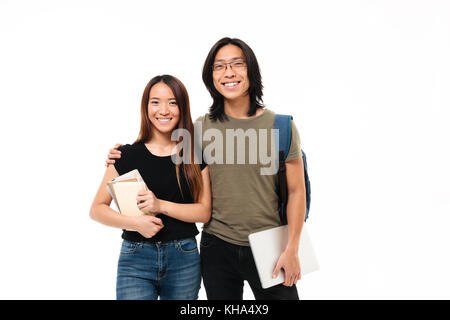Portrait of a young smiling couple étudiants asiatiques avec sac à dos tenue de livres et de coffre en position debout et à la caméra à l'arrière droit Banque D'Images