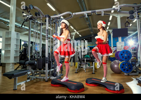 Deux sporty girls au père noël de costumes à la salle de sport de Noël Banque D'Images