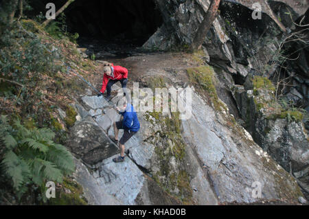 Un couple climbing descendait du peu de rydal cave en utilisant une corde au-dessus de l'eau dans le rydal parc national de lake District, Cumbria, Royaume-Uni. Banque D'Images