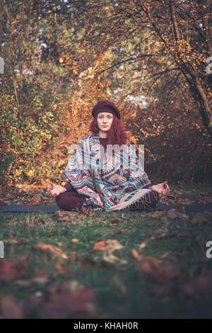 Fille sur un jour d'automne la pratique du yoga à l'extérieur, assis dans le facile (bon, agréable) posent (sukhasana) Banque D'Images