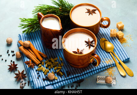 Masala chai latte thé indien chaud cérémonie traditionnelle du thé de lait sucré avec des épices, des herbes infusion bio boisson santé dans la porcelaine tasse sur bleu Banque D'Images