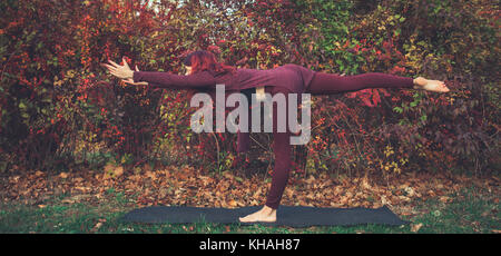 Fille sur un jour d'automne la pratique du yoga en plein air, faisant poser 3 guerrier (virabhadrasana iii) Banque D'Images