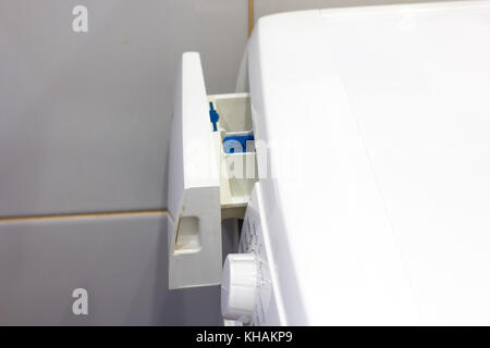 Femme jette de lessive dans une machine à laver de près. Banque D'Images