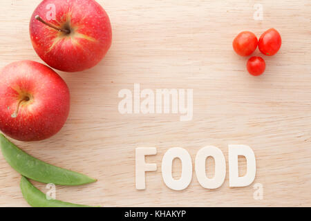 Pommes rouges frais, haricots verts et tomates cerise sur la planche à découper en bois avec word la nourriture. copyspace. Banque D'Images