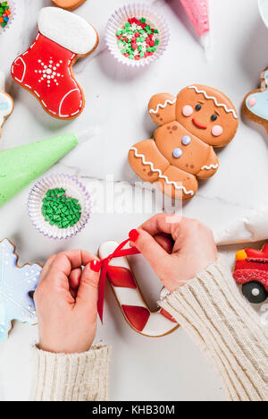 Préparation à Noël, la jeune fille (les mains dans l'image) décore des épices traditionnelles faites à la main avec le sucre glace, en biscuit multicolores Banque D'Images