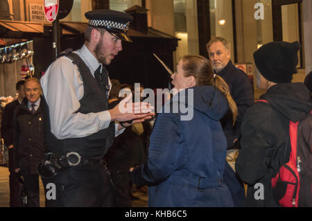 Londres, Royaume-Uni. 14 novembre 2017. Un policier parle à une femme, à l'extérieur de l'entrée souhaitée au magasin après la sécurité se sont plaints de la manifestants comme ils suivre la campagne de fermer l'ouverture récente du Regent St London flagship store du Canada Goose avec le premier 'secrète' aléatoire de protestations, de détails seulement partagée dans un groupe privé, qu'elle a l'intention de monter ensemble avec des manifestations samedi. Crédit : Peter Marshall/Alamy Live News Banque D'Images