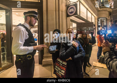 Londres, Royaume-Uni. 14 novembre 2017. Un policier parle à une femme, à l'extérieur de l'entrée souhaitée au magasin après la sécurité se sont plaints de la manifestants comme ils suivre la campagne de fermer l'ouverture récente du Regent St London flagship store du Canada Goose avec le premier 'secrète' aléatoire de protestations, de détails seulement partagée dans un groupe privé, qu'elle a l'intention de monter ensemble avec des manifestations samedi. Crédit : Peter Marshall/Alamy Live News Banque D'Images