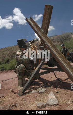 5 juillet 2006 - Nogales, Arizona, États-Unis - le Sgt. De la Garde nationale de l'armée de l'Arizona, de première classe Gustavo Dagino, sourie des pièces d'une barrière de véhicule près de la frontière entre les États-Unis et le Mexique à Nogales, en Arizona, le 5 juillet 2006. Les voies ferrées utilisées empêchent les véhicules de passeurs de drogue et de personnes de traverser la frontière. Une partie de la bordure est visible en arrière-plan. L'Arizona a déployé 300 membres le long de la frontière internationale de l'État dans le cadre de l'opération Jump Start, l'effort fédéral visant à utiliser des membres de la garde pour faire des travaux non-paral, soulager les agents de patrouille frontalière pour les tâches de patrouille. (Image crédit : © R Banque D'Images