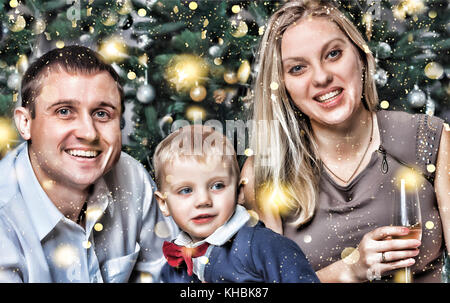 Heureux jeune famille avec un petit sourire heureux fils répond à la nouvelle année à la maison. arbre de Noël, décorations et cadeaux de Noël Nouvel an.. Banque D'Images