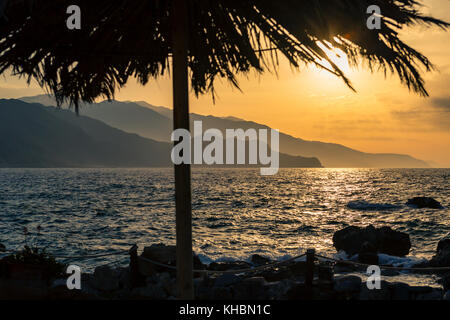 Des belles montagnes paysage avec palmier en mer, côte, plage et les rochers, de hautes montagnes en arrière-plan au lever du soleil sur l'île de Crète, gr Banque D'Images