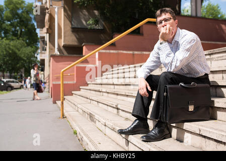 Portrait d'un homme d'affaires s'ennuyer assis sur des escaliers. Banque D'Images