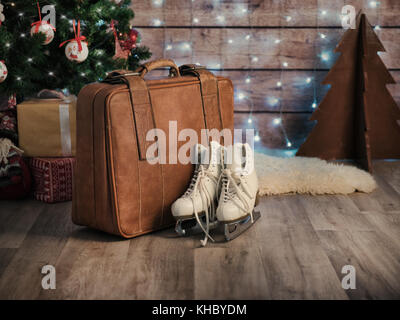 Patins de la femme à côté d'une vieille valise en cuir et un arbre de Noël. Décorations de Noël Banque D'Images