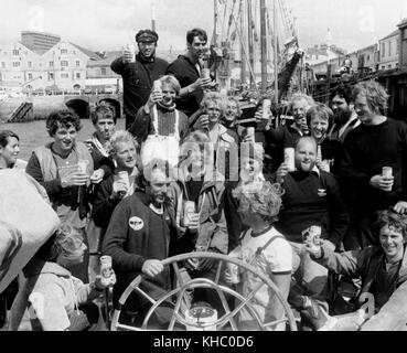 AJAXNETPHOTO. 14 AOÛT 1979. PLYMOUTH, ANGLETERRE. - FASTNET RACE 1979 - ÉQUIPAGE DU CONDOR DES BERMUDES AVEC LE SKIPPER PETER BLAKE (NZL) (CENTRE, DERRIÈRE LE VOLANT.) CÉLÉBRER LA VICTOIRE À L'ARRIVÉE EN TOUTE SÉCURITÉ À LA FIN DE LA COURSE. PROPRIÉTAIRE BOB BELL 2E À DROITE DANS LA RANGÉE DU MILIEU, DEVANT ROB JAMES ; ANDREW SPEDDING, ÉCRIVAIN ET DESSINATEUR, EST EN HAUT À GAUCHE. PHOTO:JONATHAN EASTLAND/AJAX REF:WPXBW791408 Banque D'Images